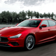 A photo of a red Maserati Ghibli sedan driving on a race track.